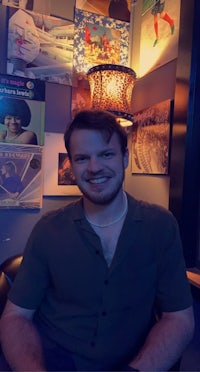 a man sitting in a chair in front of a wall of pictures