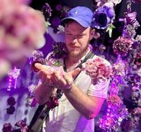 a man in a blue hat holds a bunch of purple flowers